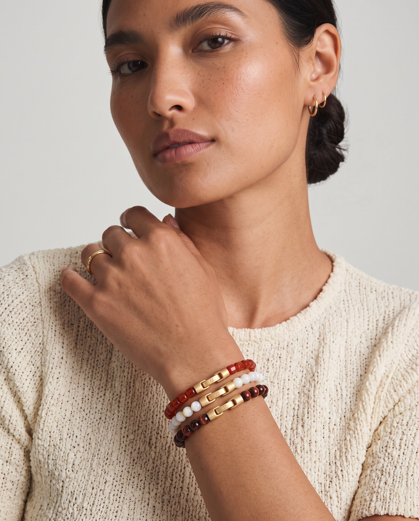 Ember, Lumen and Mocha bracelets stacked on a wrist, hand at the collarbone