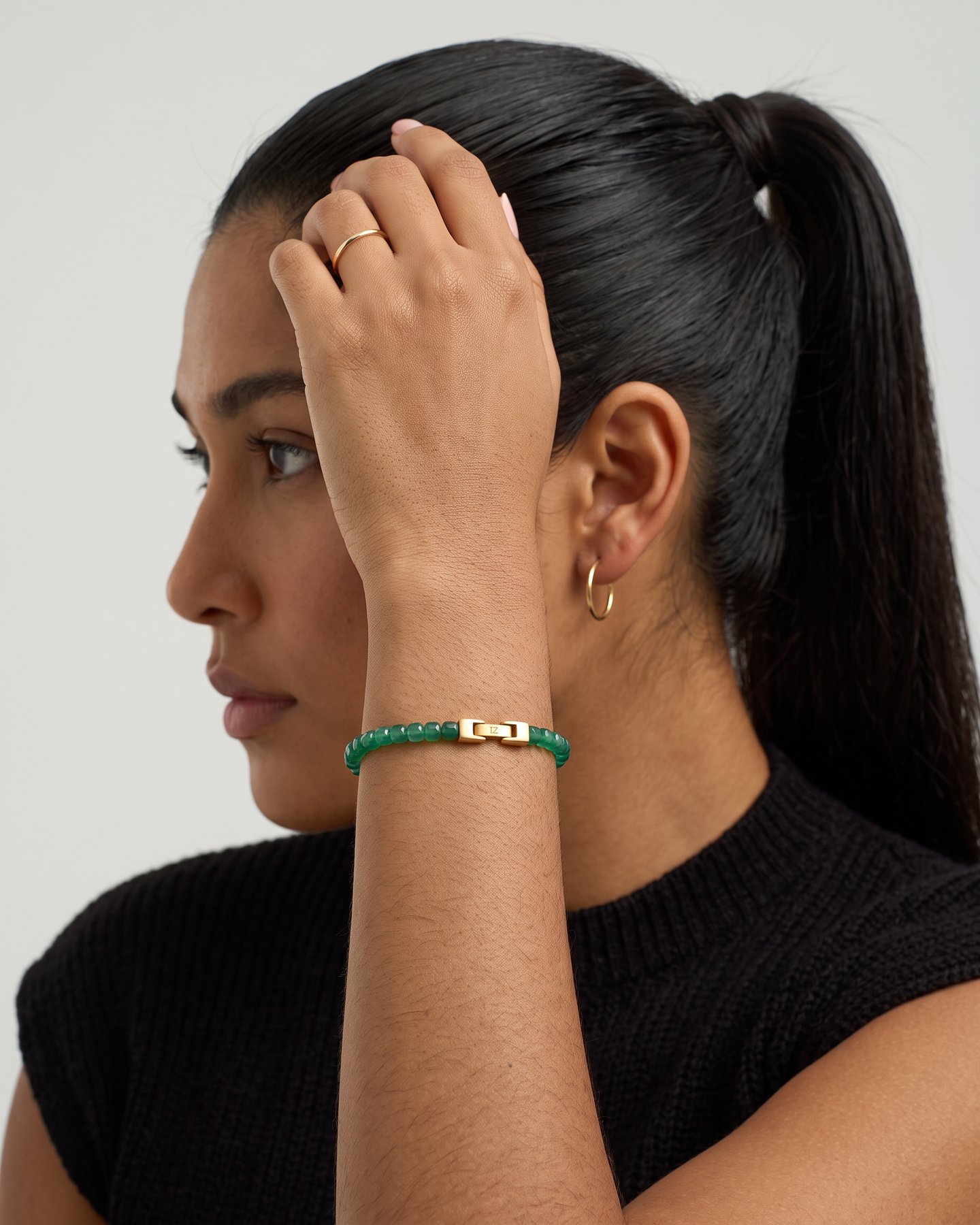 Sage green agate bracelet on a raised wrist, black knit top