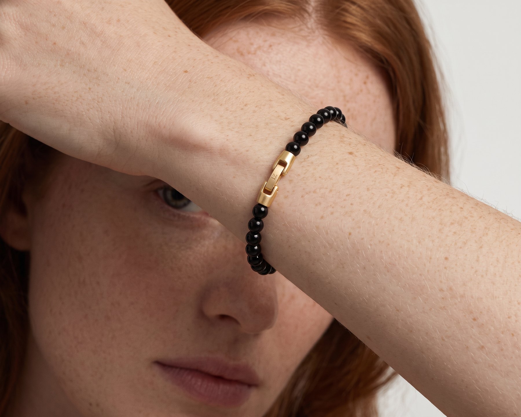 Noir black onyx bracelet on a forearm across the brow