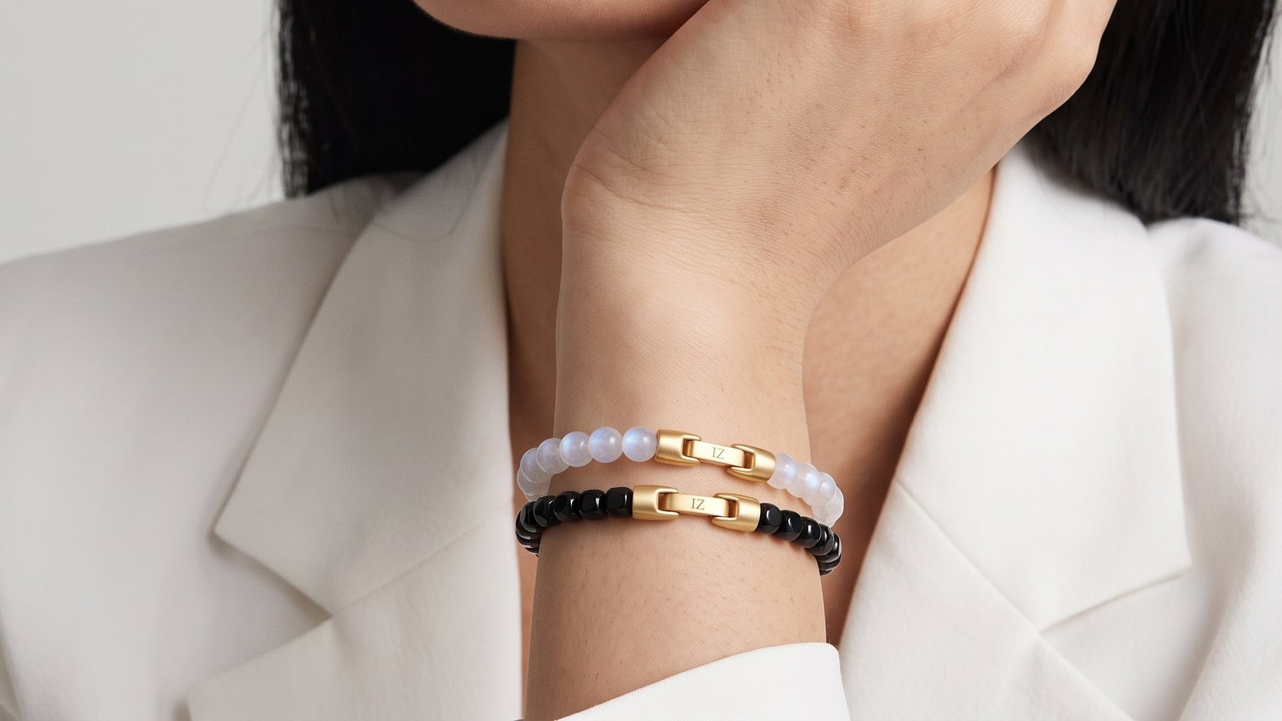 Luna and Ink bracelets stacked, hand against the cheek, white blazer